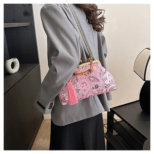 Detail of pink paisley clutch featuring bamboo handle and elegant pink tassel accents