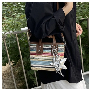 Detail of colorful woven tote with brown leather straps and star charm accessory