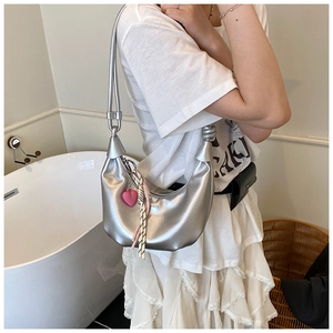 Détail du sac à bandoulière croissant argenté à texture métallique et charme coeur