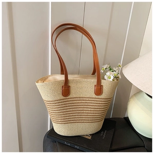 Detail der handgewebten Strohtasche mit braunen Lederriemen und gestreiftem Design