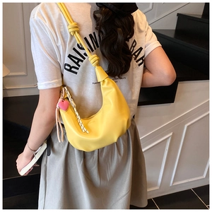 Détail du sac croissant en cuir jaune vif avec breloque cœur rose et bandoulière nouée