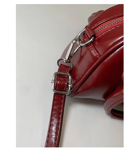 Detail of silver metal buckle and lobster clasp on red glossy leather handbag strap