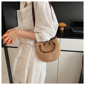Detail of hand-woven bucket bag with crochet smiley face and brown contrast strap