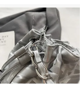 Détail d'un sac seau argenté avec motif géométrique en Y et chaîne en métal brillant