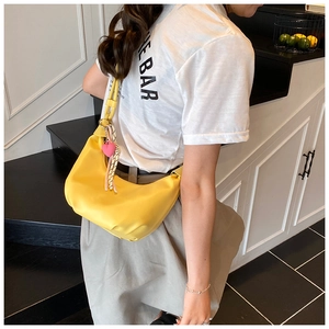 Détail du sac hobo jaune avec pendentif coeur rose et accessoire tissé à rayures