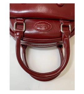 Detailed close-up of dark wine red glossy leather handbag featuring silver hardware and handles