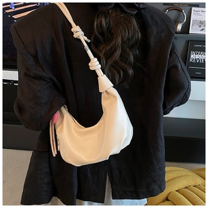 Détail du sac hobo crème avec nœud d'épaule et pendentif cœur sur un blazer