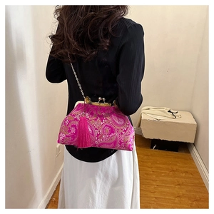 Detailed close-up of fuchsia silk embroidery bag with golden floral pattern and tassel