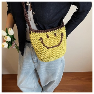 Close-up of a yellow knitted bucket bag with a brown smiling face and woven strap
