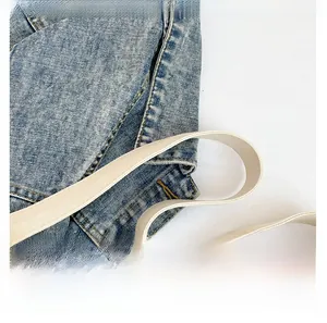Close-up of wide canvas shoulder strap and blue washed denim fabric detail of tote bag
