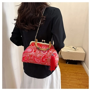 Red paisley shell bag with bamboo handle and fringe tassel shown on a model