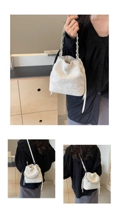 Détail d'un sac seau blanc avec imprimé lettres et poignée en chaîne argentée pour femme