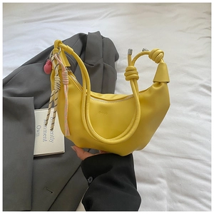 Détail du sac hobo jaune avec poignée nouée et pendentif tissé coloré