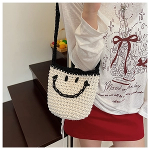 Close-up of handmade crochet bucket bag with a smiley face design and black straps