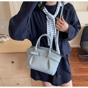 Close-up of light blue lychee pattern leather bucket bag with ZHIMU logo and buckle detail