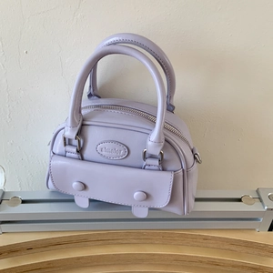 Detail view of the lavender leather handbag featuring embossed logo and silver zipper