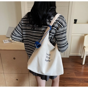 Sac cabas en toile blanc cassé avec texte artistique et ruban bleu sur le modèle