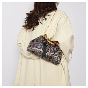 Detail of vintage paisley clutch with black tassels, bamboo clasp, and gold chain strap