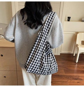 Detailed back view of a large black and white gingham canvas tote bag worn by a model