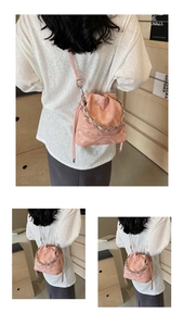 Détail du sac seau rose avec cordon de serrage, chaîne argentée et surface texturée