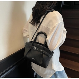 Detail of black lychee grain leather bucket bag with ZHCNMA logo and silver buckle