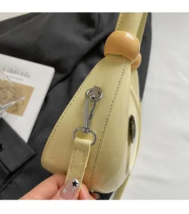 Detailed macro of pale yellow patent leather crescent bag with silver hardware and beads