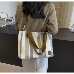 Detailed back view of a striped canvas tote bag with adjustable brown shoulder strap