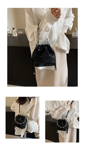 Détail du sac seau noir à cordon avec texture gaufrée et bandoulière en chaîne