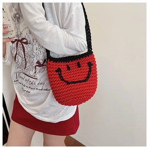 Detail of red hand-woven bucket bag with black smiley face and matching knit strap