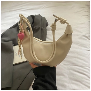 Détail du sac croissant beige avec pendentif coeur rose et bandoulière nouée