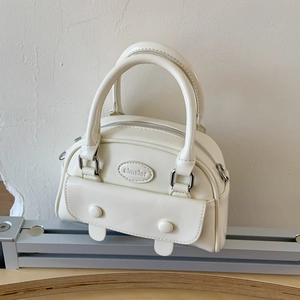 Detail view of cream white PU leather handbag featuring a debossed logo and silver hardware