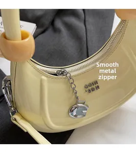 Detail of butter yellow crescent bag featuring silver zipper and glossy patent leather