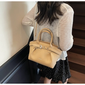 Close-up of beige lychee leather bucket bag with gold buckle and brand logo