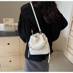 Détail du sac seau blanc en cuir texturé avec une chaîne décorative argentée chic