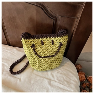 Detail of the lime green hand-knitted smiley face bucket bag on a white background