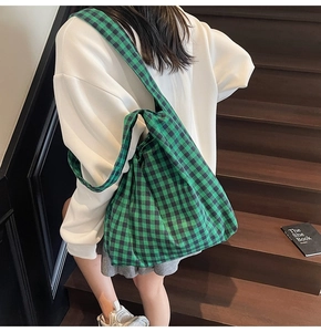 Detailed view of the green and black gingham canvas tote bag with wide shoulder strap