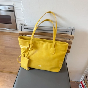 Detail of yellow tote bag with PANTOR logo and matching mini zipper pouch on metal chair