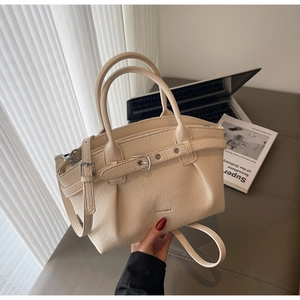 Close-up of beige lychee textured handbag with decorative buckle and dual handles