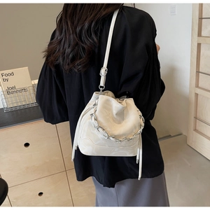 Détail du sac seau crème avec cordon, motif géométrique et chaîne argentée sur modèle
