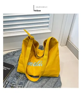Detail of yellow canvas tote bag with blue mali embroidery on denim jacket background