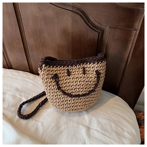 Detailed view of handcrafted knit bucket bag featuring a woven smiley face pattern