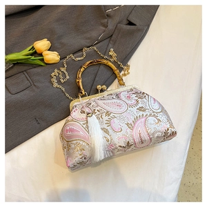 Detail of vintage paisley satin handbag with bamboo handle, gold chain and white tassel