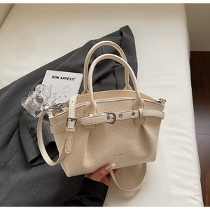 Detailed macro view of cream lychee texture leather handbag with metal buckle strap