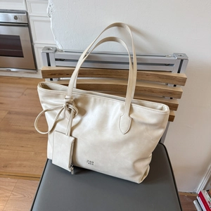 Detail of off-white leather tote bag with a small matching zipper pouch and logo