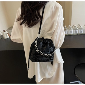 Détail du sac seau noir avec chaîne argentée et cordon de serrage porté par un mannequin