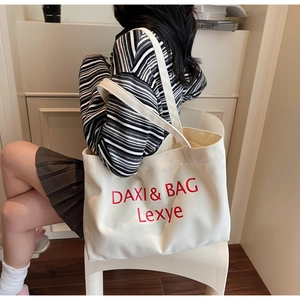 Detailaufnahme einer großen cremefarbenen Canvas-Tasche mit roter Stickerei