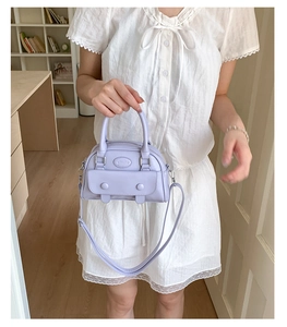 Lavender purple mini Boston bag with decorative buttons shown on white lace dress