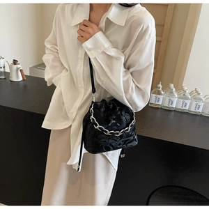 Sac seau noir chic avec chaîne argentée porté par un mannequin dans un cadre intérieur