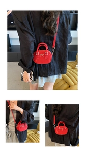 Close-up of red mini bowling bag with silver bow detail and detachable strap