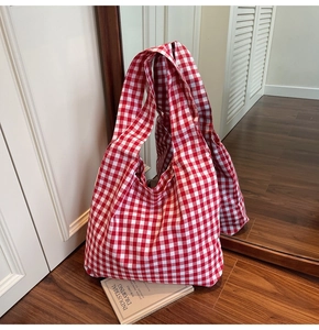 Detailed view of red and white checkered canvas tote bag placed on dark wood floor